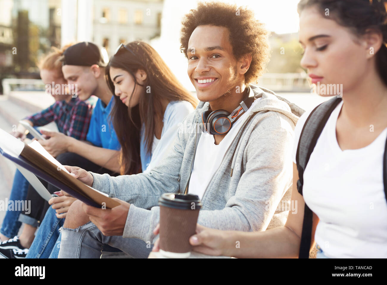 Cheerful black student studying outdoor with groupmates Stock Photo