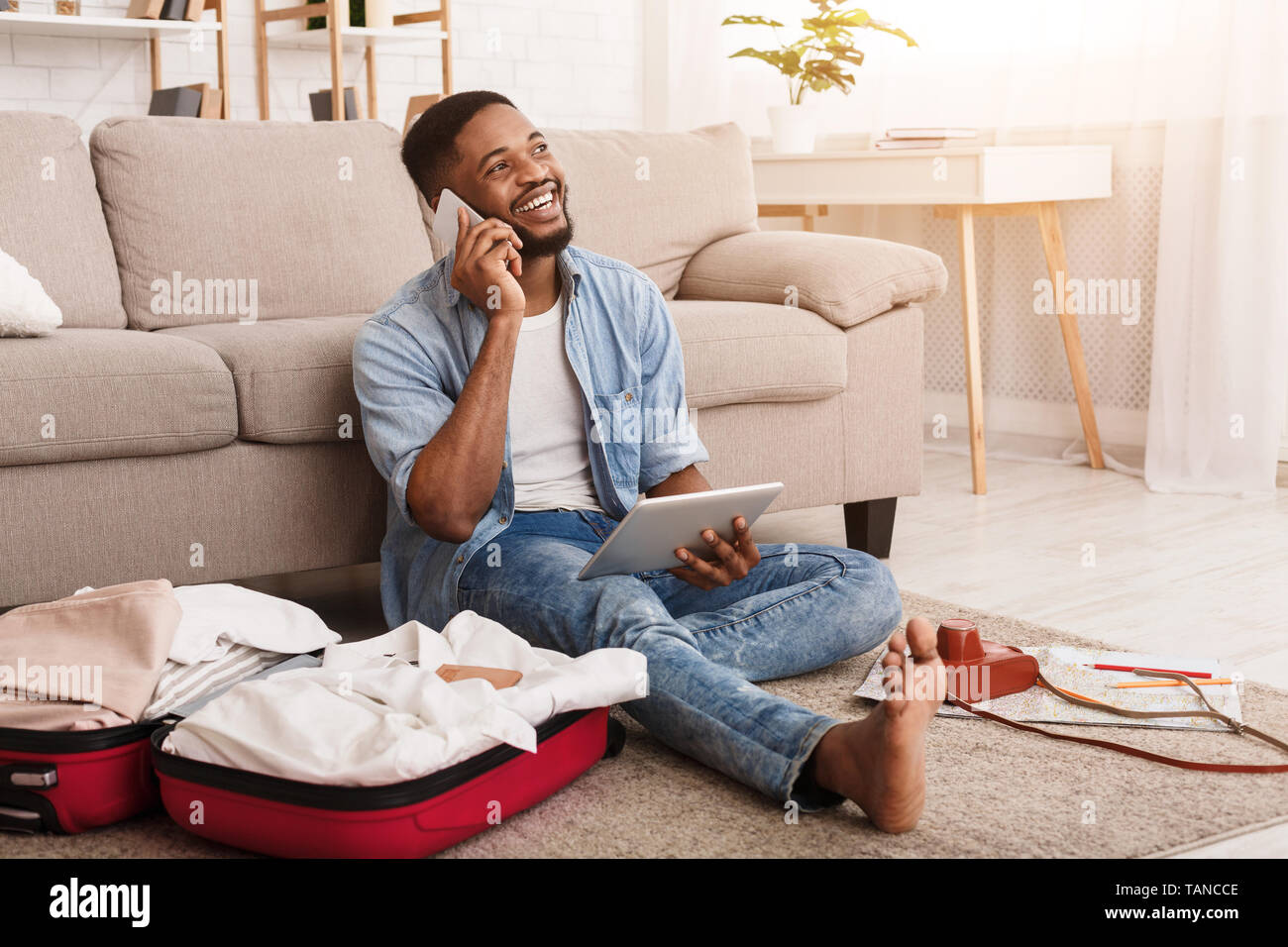 Afro Man Preparing For Vacation, Consulting With Agent Stock Photo