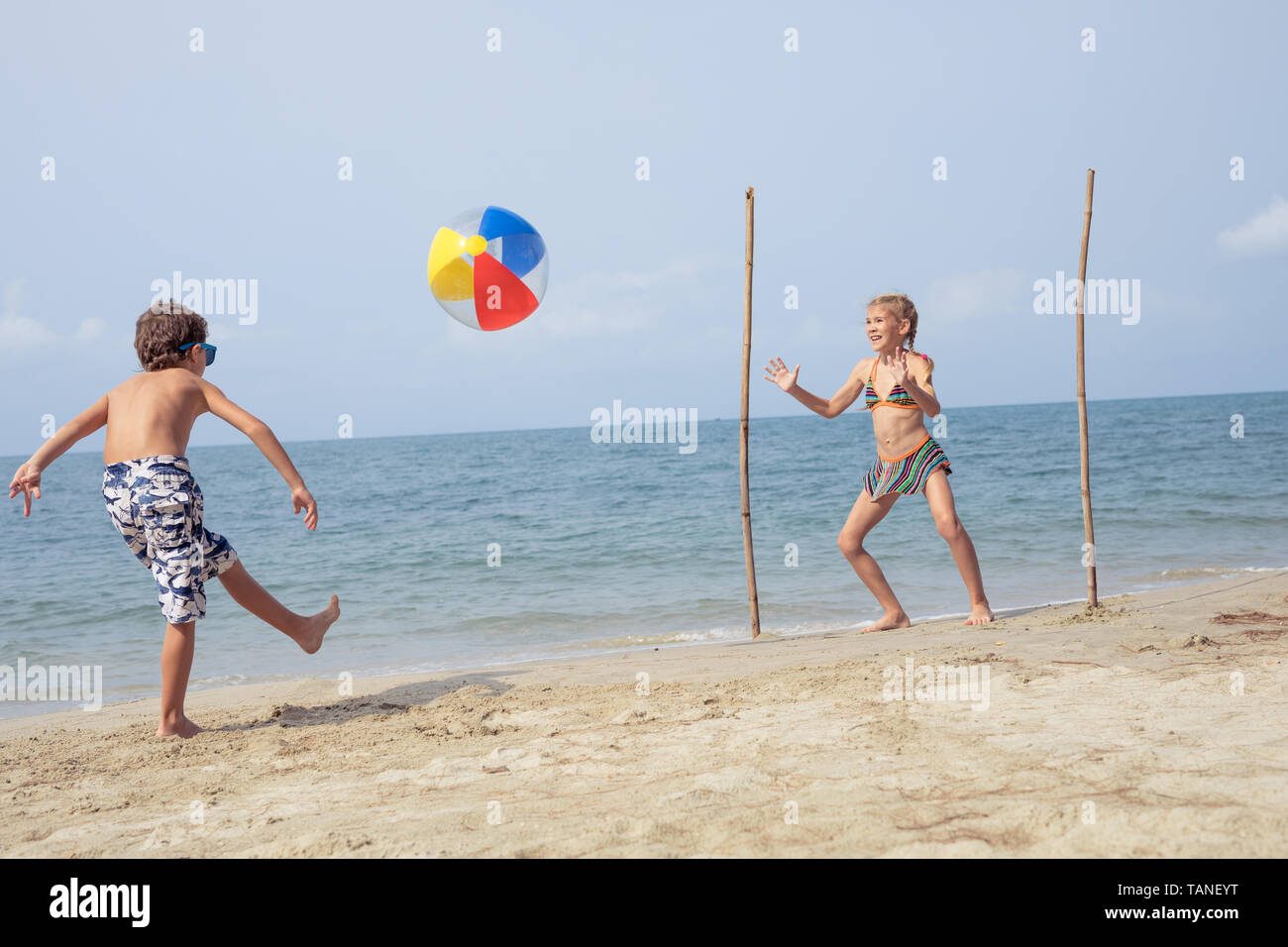 Two happy little children playing on the beach at the day time.  Kids having fun outdoors. Concept of kids on vacation and friendly family. Stock Photo