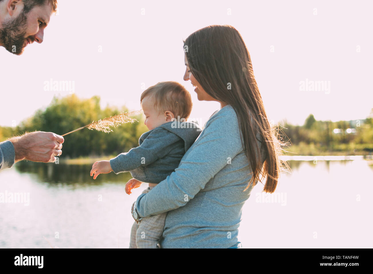 Happy family with Cute baby boy on the lake water background outdoors