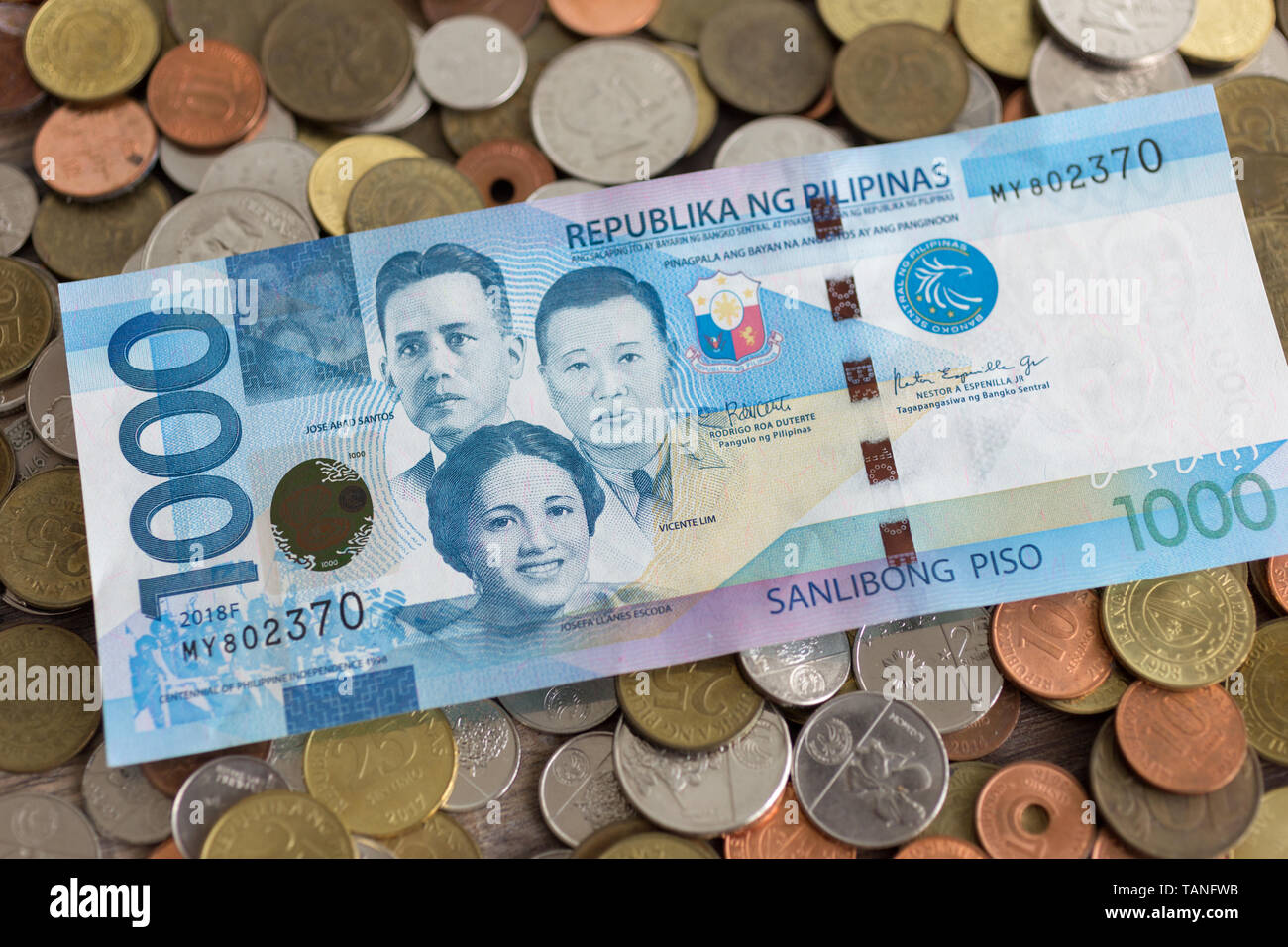 A pile of new and old Philippine peso coins with one thousand banknote on it Stock Photo