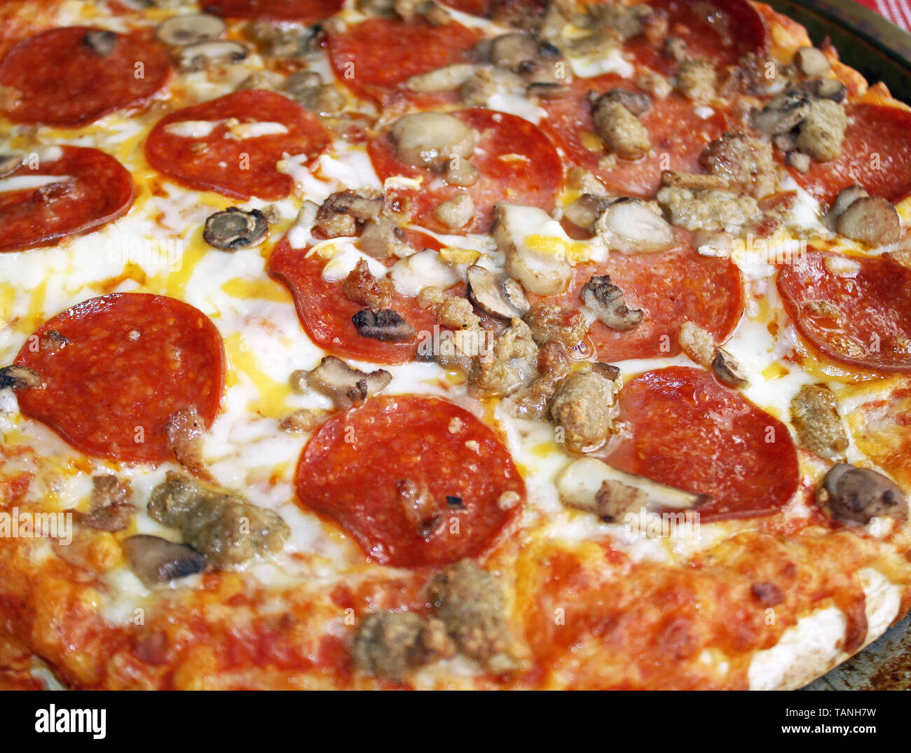 Fresh hot pizza with pepperoni, sausage, mushrooms and melted mozzarella cheese Stock Photo