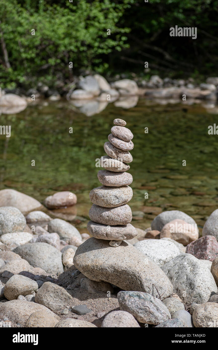 Balanced stones stack near a river and with a forest in background, Zen meditation spa relaxation background Stock Photo