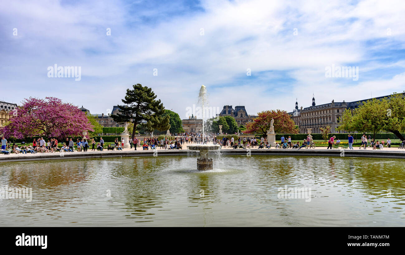 The fountain in the Grand Bassin Rond of the Jardin des Tuileries with the Louvre in the background on a sunny spring day Stock Photo
