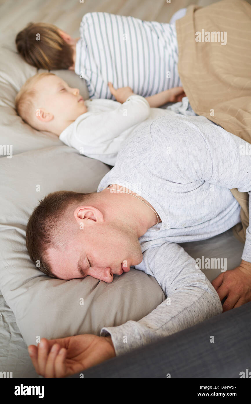 Relaxed Young Family In Pajamas Lying Under Blanket On Soft