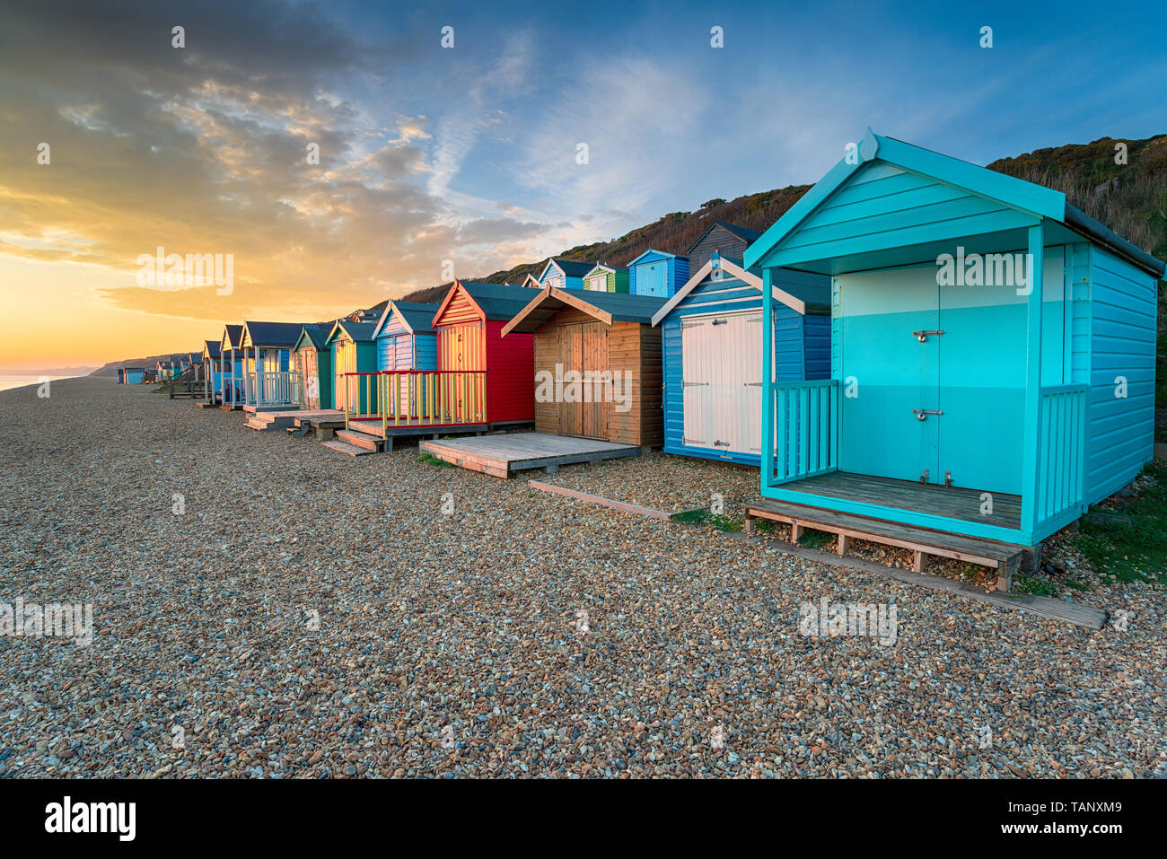 Stunning sunset over a row of brightly coloured beach huts at Milford on Sea on the Hampshire coast Stock Photo