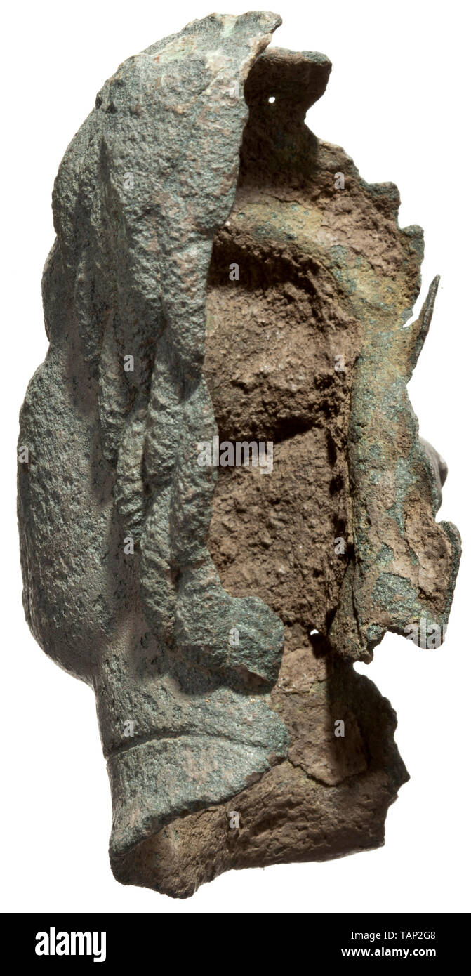 A Roman head of an African male with negroid features, 2nd - 3rd century Fragment of a bronze balsamarium. Fully preserved face of a black man with glass inlaid pupils. Also copper inlays at the edges of the lips. Around the neck a groove which held the inlay for the portrayal of a necklace. Wide nose and big lips. Coarsely modelled hair. On the upper left a palmette, onto which the ring of the missing handle was soldered. Surface slightly corroded. Fine, even olive-green patina. Height 10.5 cm. Excellent style of high quality with distinctive po, Additional-Rights-Clearance-Info-Not-Available Stock Photo