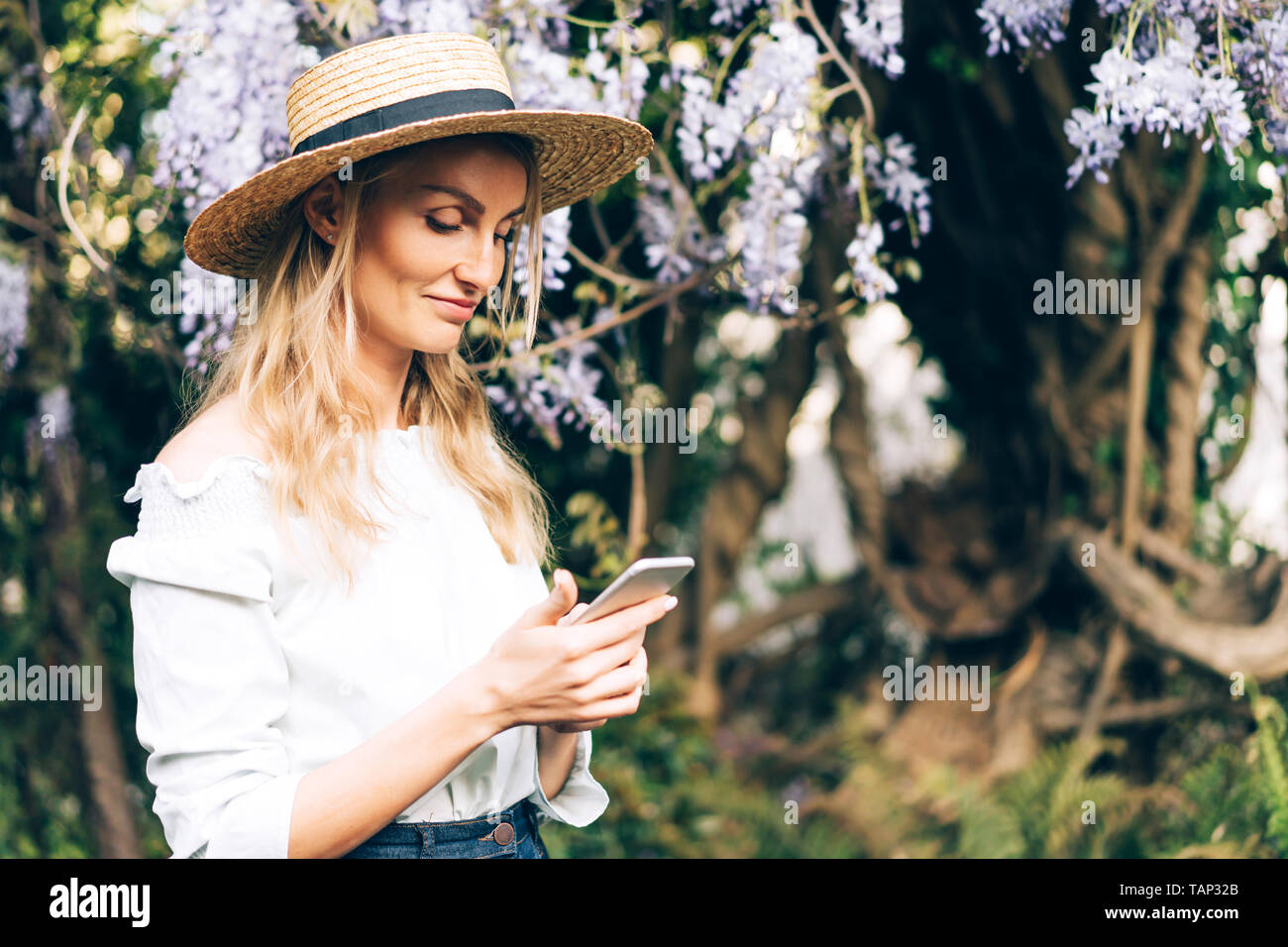 The girl in a romantic mood in the park reads sms message in the phone. Stock Photo