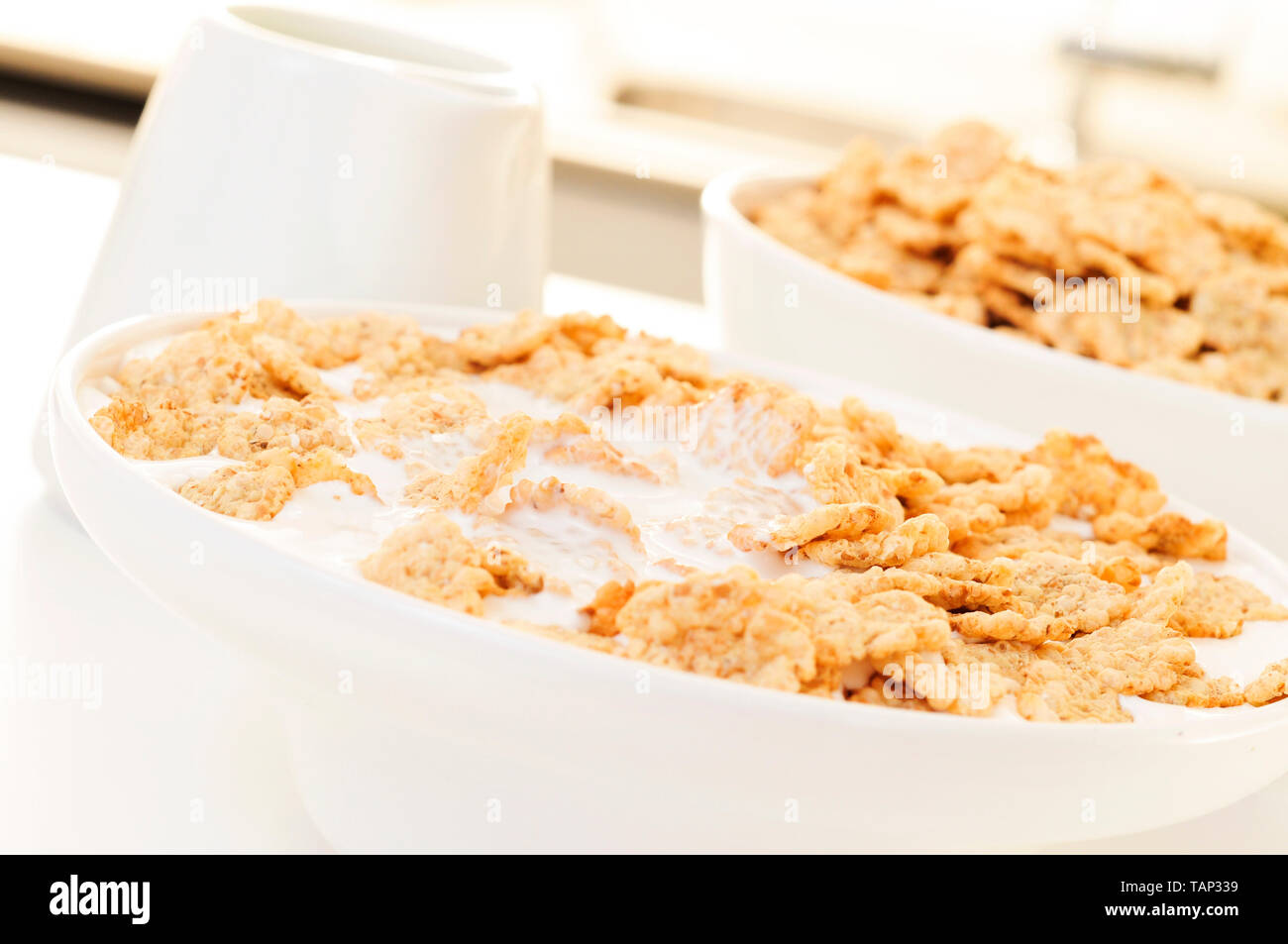 closeup of a bowl with breakfast cereals soaked in milk or drinkable yogurt, on a table set for breakfast Stock Photo