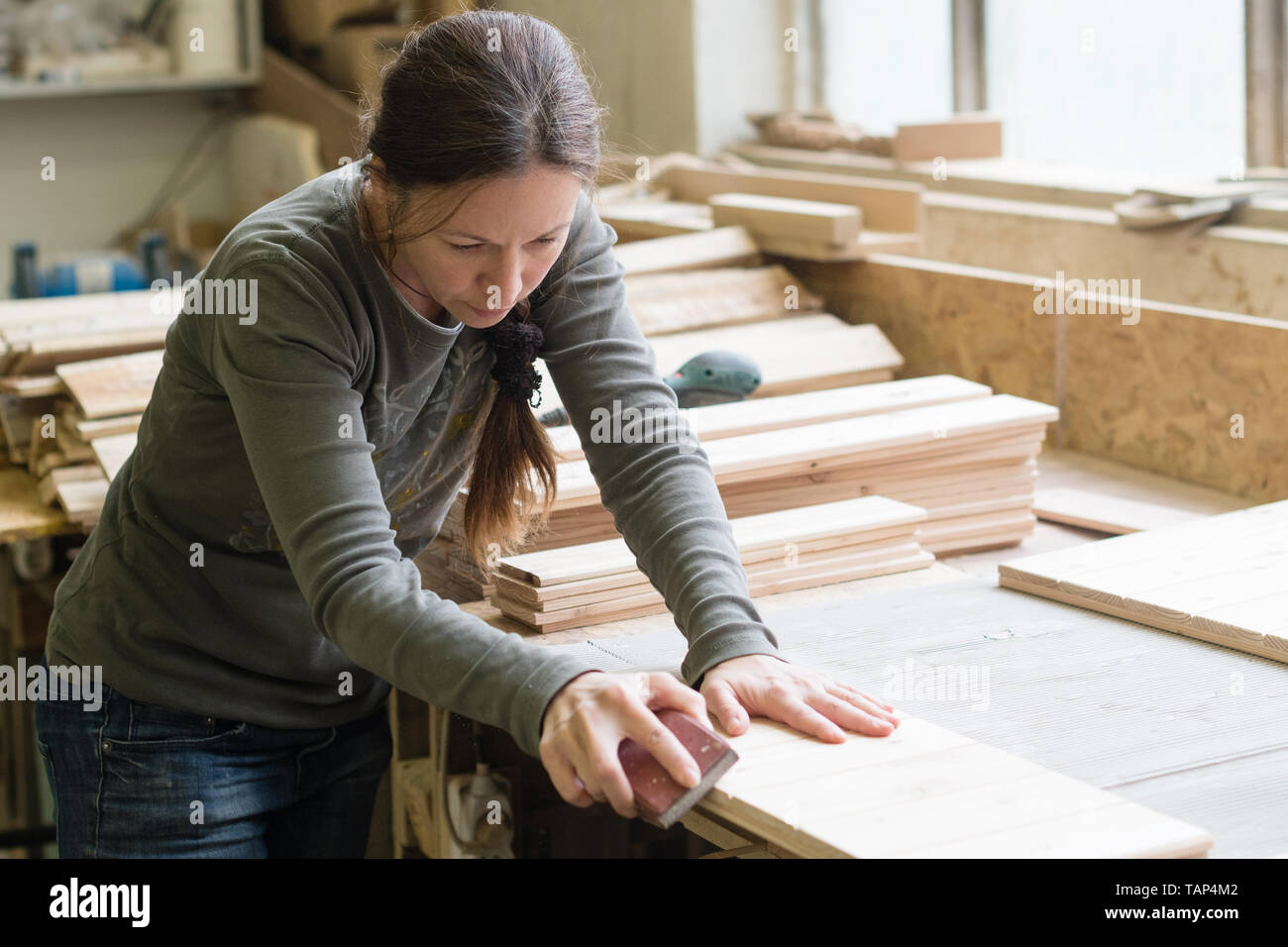 Young woman sanding wooden board using sand paper at Stock Photo Alamy