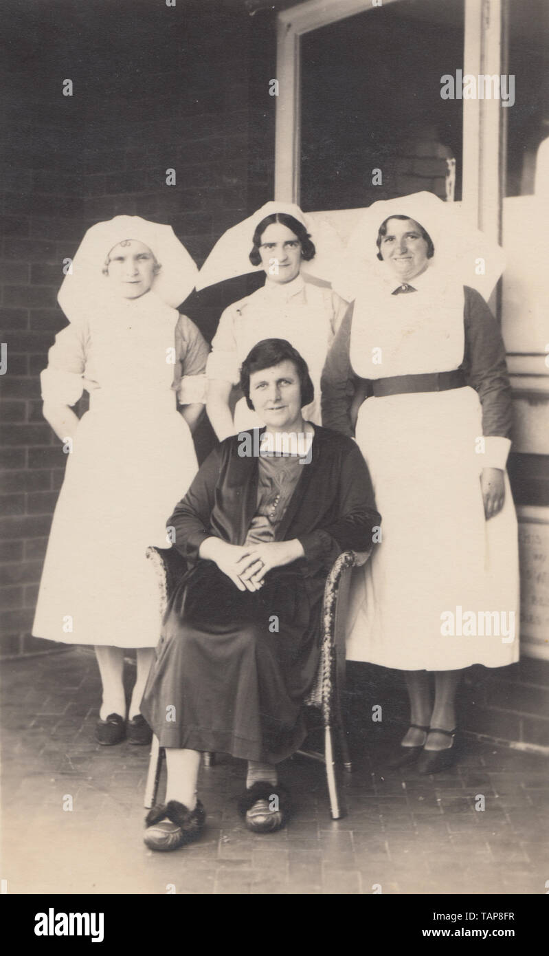 Vintage Photographic Postcard Showing Three Female Nurses and Their Female Patient. Stock Photo