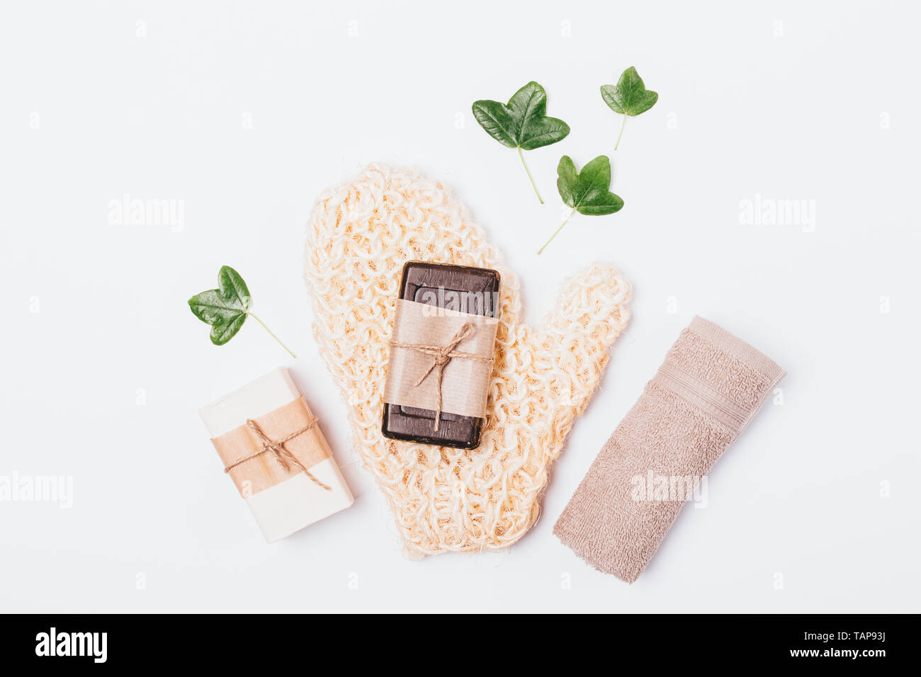 Natural Accessories And Bath Soap Next To Green Leaves On White