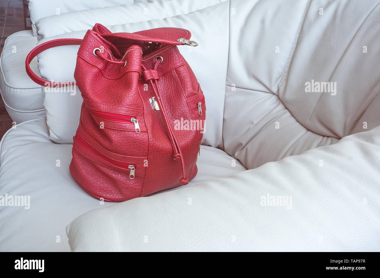 A Woman S Coral Colored Backpack Stands On A Leather White A Woman S Coral Colored Backpack Stands On A Leather White