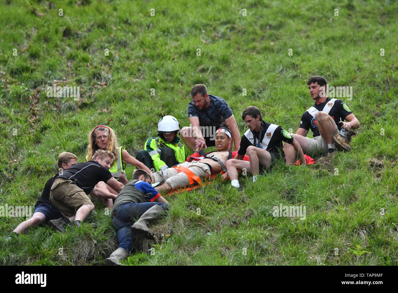 A man comes down on a stretcher after taking part in the second men's race during the annual cheese rolling competition at Cooper's Hill in Brockworth, Gloucestershire. Stock Photo