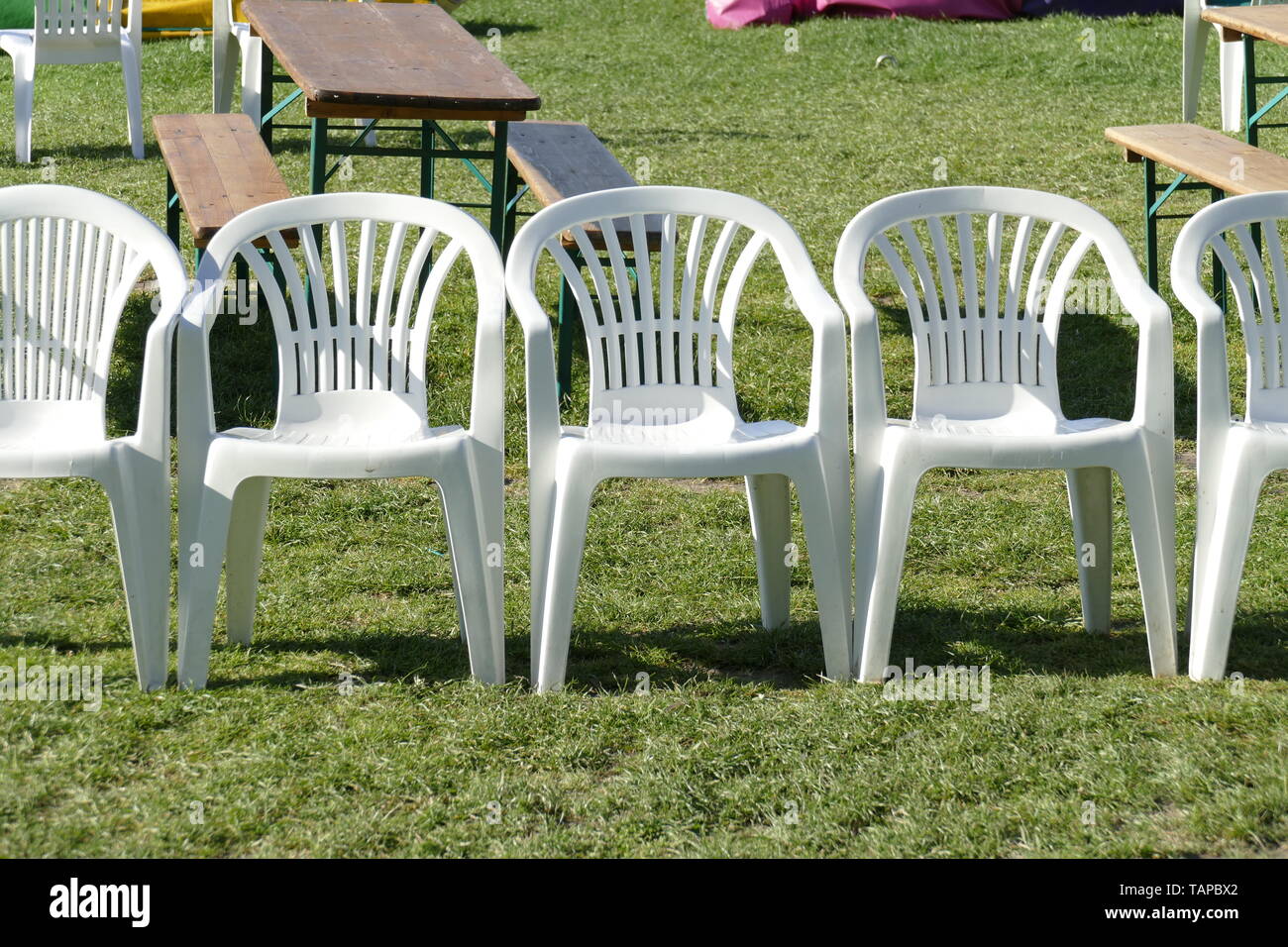 White plastic chairs standing on a meadow, Germany, Europe Stock Photo