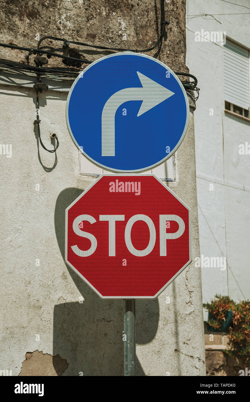 STOP and TURN RIGHT AHEAD road signs in front of worn plaster wall at