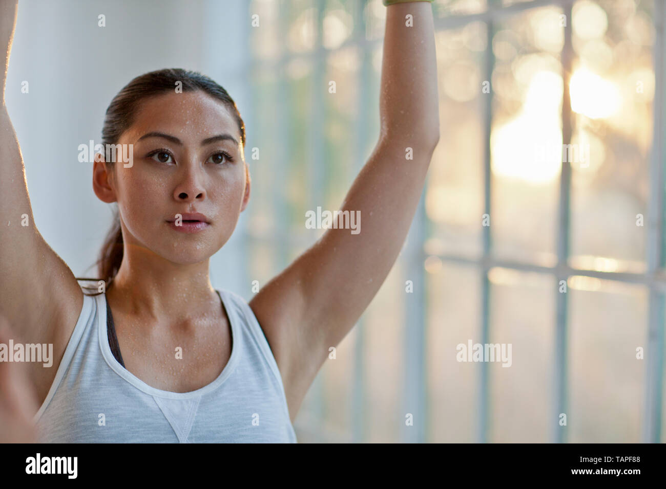 Focused young woman stretching her arms while practicing yoga. Stock Photo