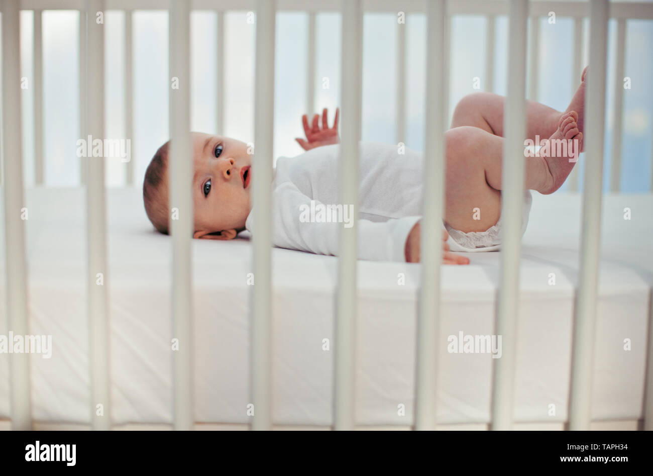 Portrait Of A Baby Boy Waving His Legs In The Air As He Lies His