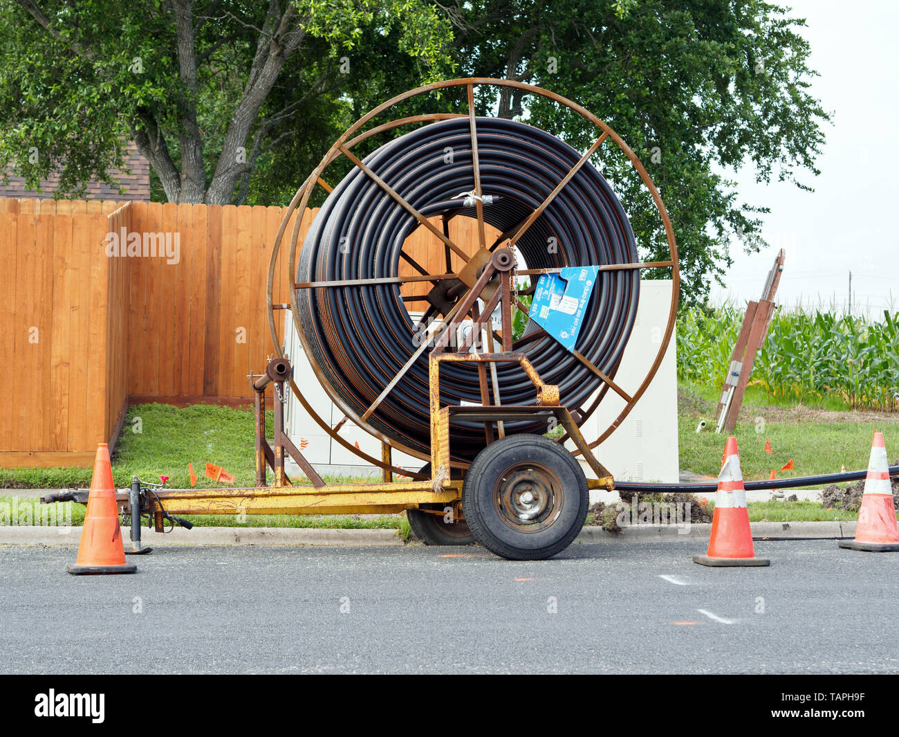 A large reel of rolled plastic conduit tubing on trailer. This is typically used for the installation of buried utility cables. Stock Photo