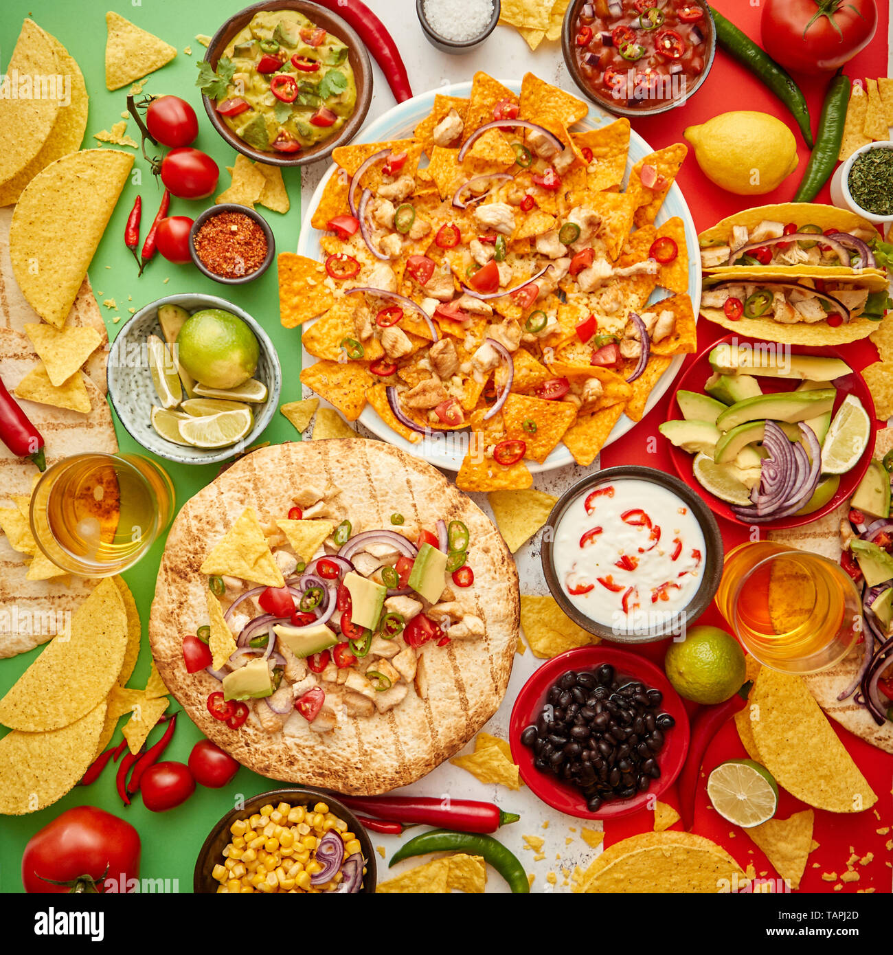 An overhead photo of an assortment of many different Mexican foods, including tacos, guacamole, nachos with grilled chicken, tortillas, salsas and oth Stock Photo