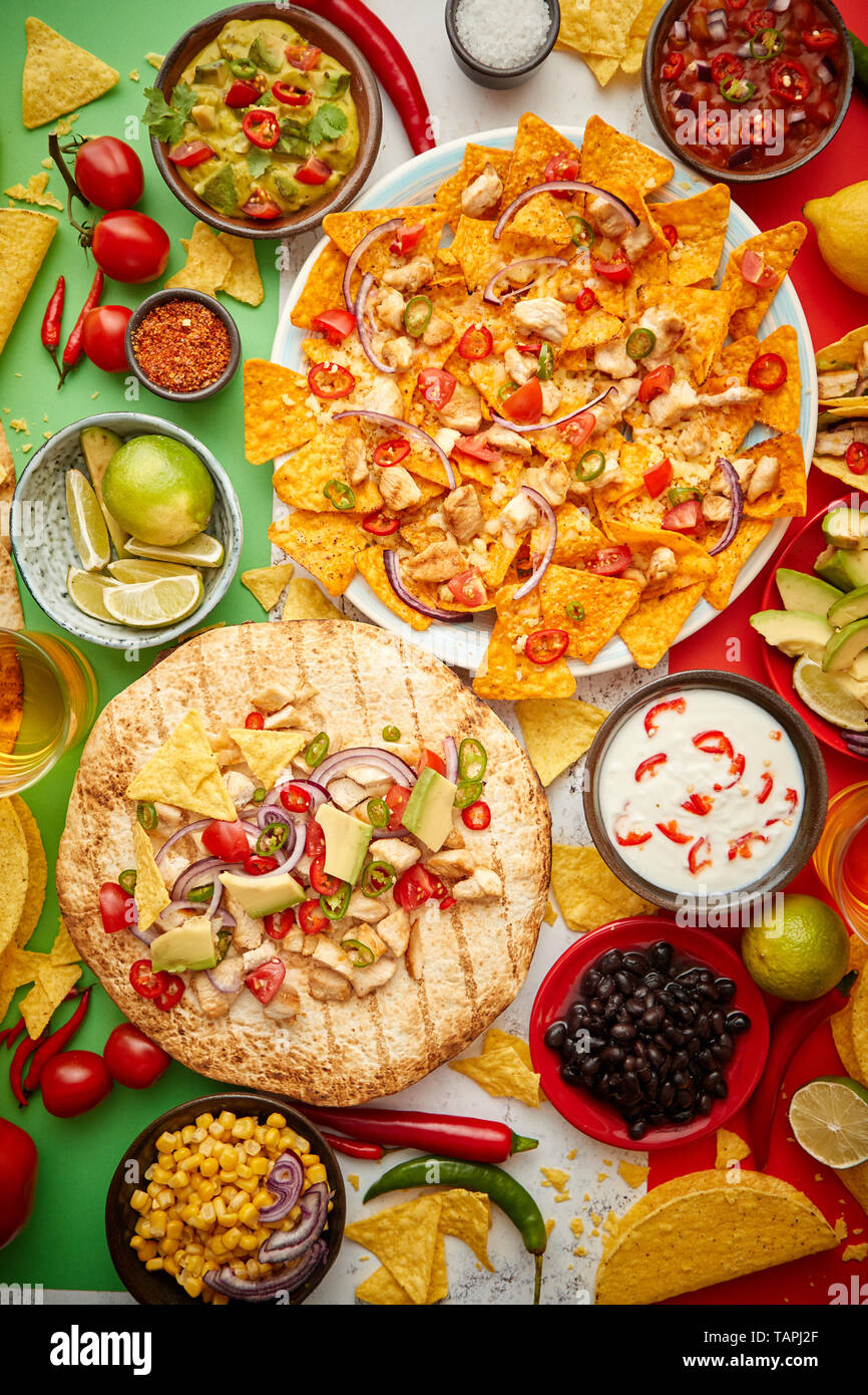 An overhead photo of an assortment of many different Mexican foods, including tacos, guacamole, nachos with grilled chicken, tortillas, salsas and oth Stock Photo