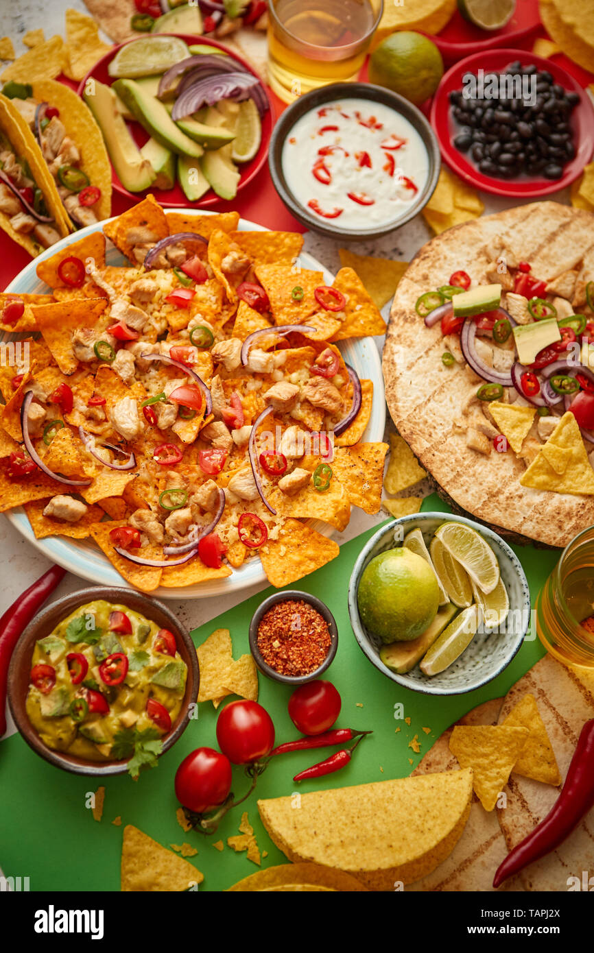 An overhead photo of an assortment of many different Mexican foods, including tacos, guacamole, nachos with grilled chicken, tortillas, salsas and oth Stock Photo