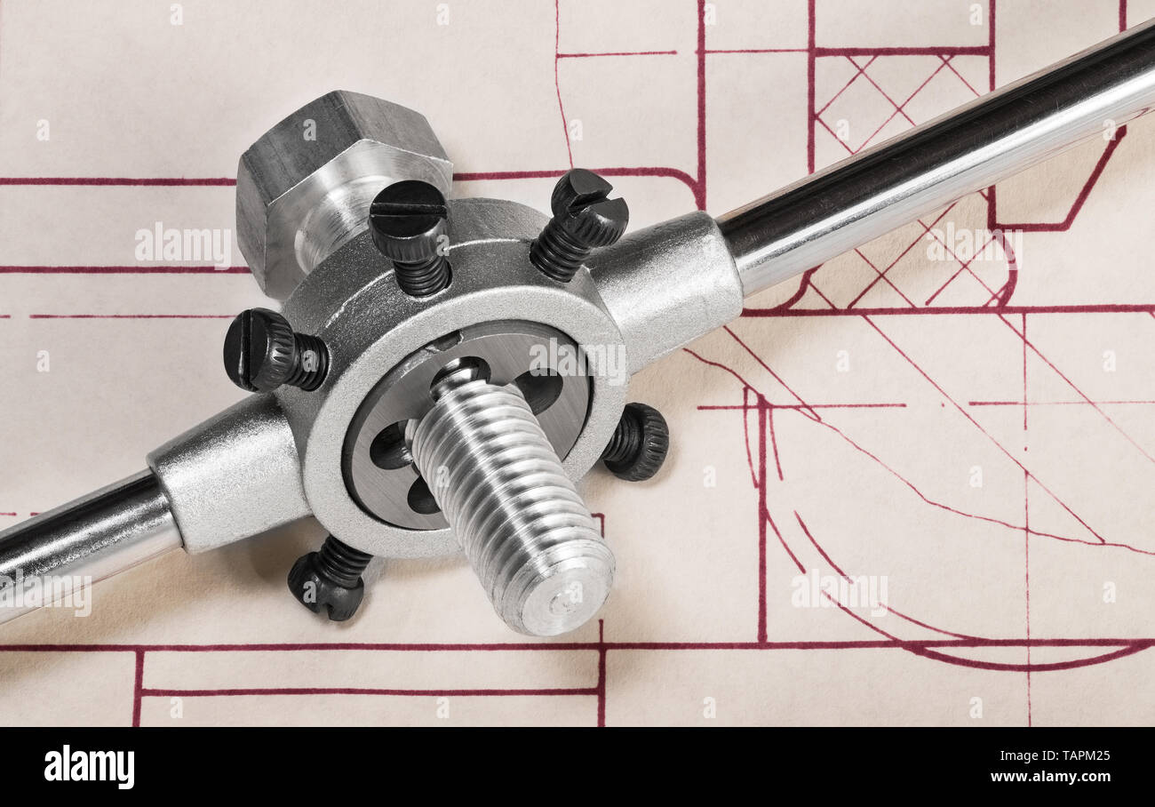 Threading die in tap wrench on technical drawing detail. Steel cutting tool when working thread on metal bolt shaft. Planning of draft. Chip machining. Stock Photo