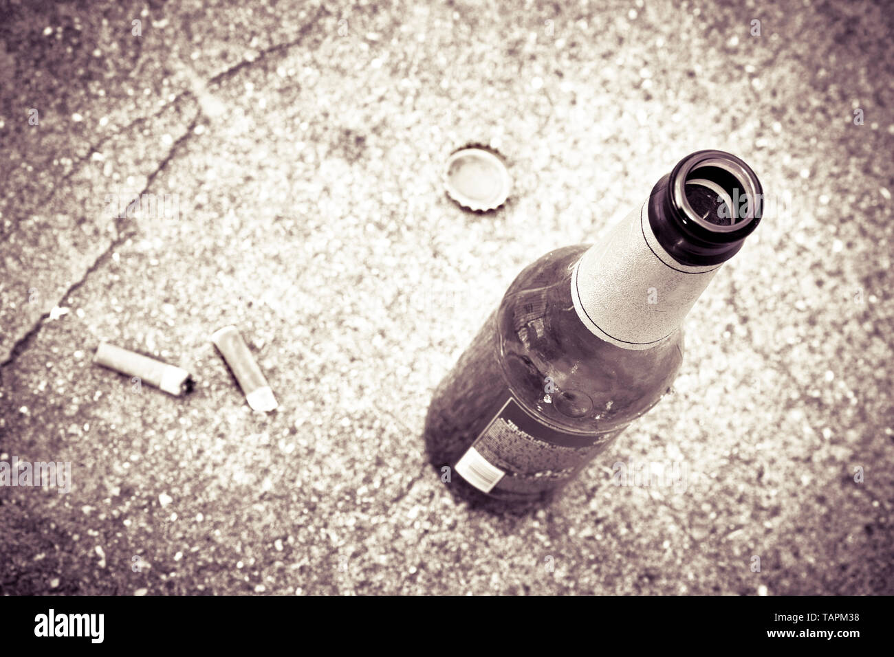 Bottle of beer resting on the ground with three cigarette's butts ...