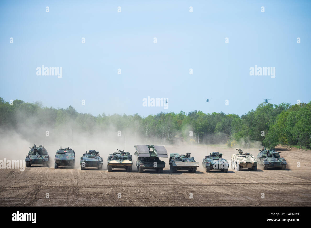 20 May 2019, Lower Saxony, Munster: During a demonstration of the Very High Readiness Joint Task Force (VJTF), tanks of the type Panzerhaubitze 2000 (l-r), GTK Boxer, Marder infantry fighting vehicle, 2A1 Dachs pioneer tank, Leguan bridge tank are in operation, Pioneer tank 2A1 badger, infantry fighting vehicle Marder, GTK Boxer and howitzer 2000 and fly helicopters of the types combat helicopter Tiger (l-r), Sea Lynx Km 88 A and multipurpose helicopter NH 90 on a training field. In 2019, Germany will be responsible for the Nato rapid reaction force. Photo: Christophe Gateau/dpa Stock Photo