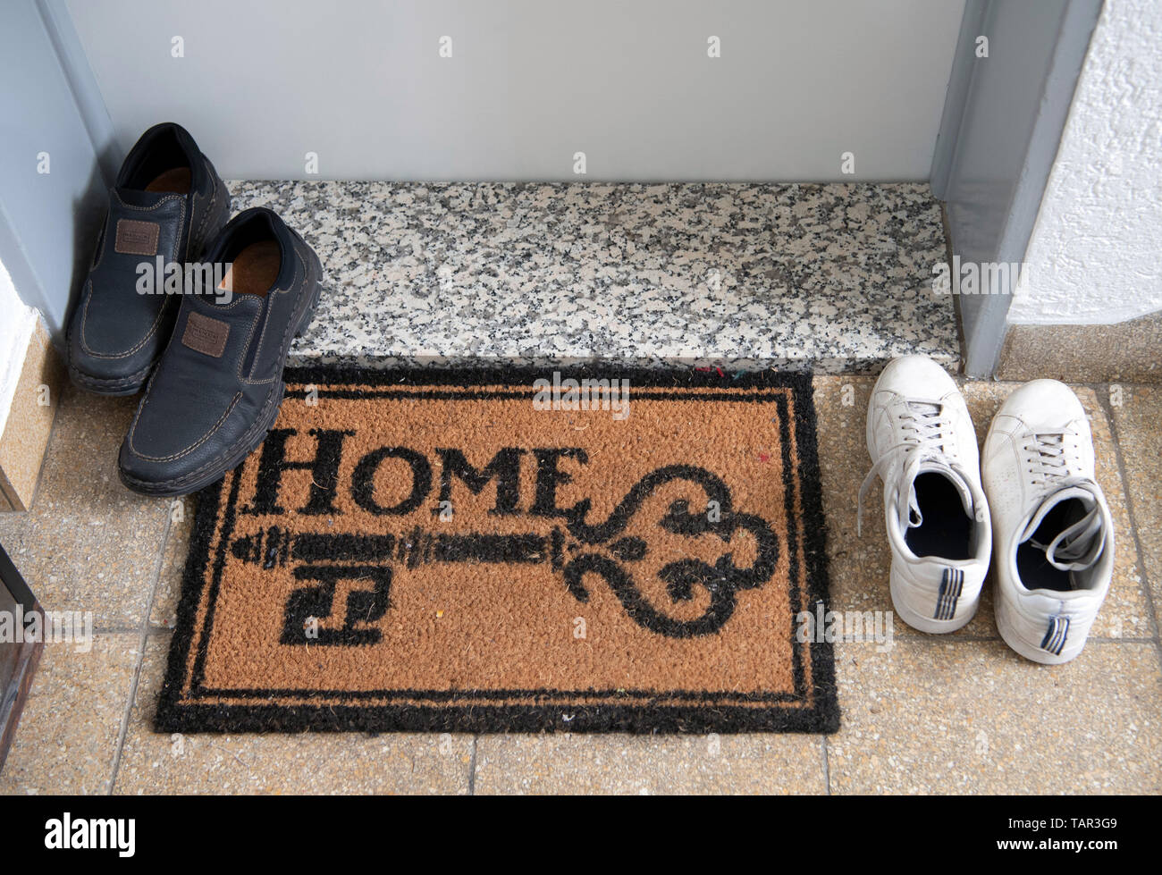 27 May 2019, Hessen, Frankfurt/Main: Two pairs of shoes stand next to a doormat with the inscription 'Home'. The installation of modular living elements on the upper floors of existing buildings is intended to create more living space in Frankfurt. (Too much focus from 27.05.2019) Photo: Boris Roessler/dpa Stock Photo