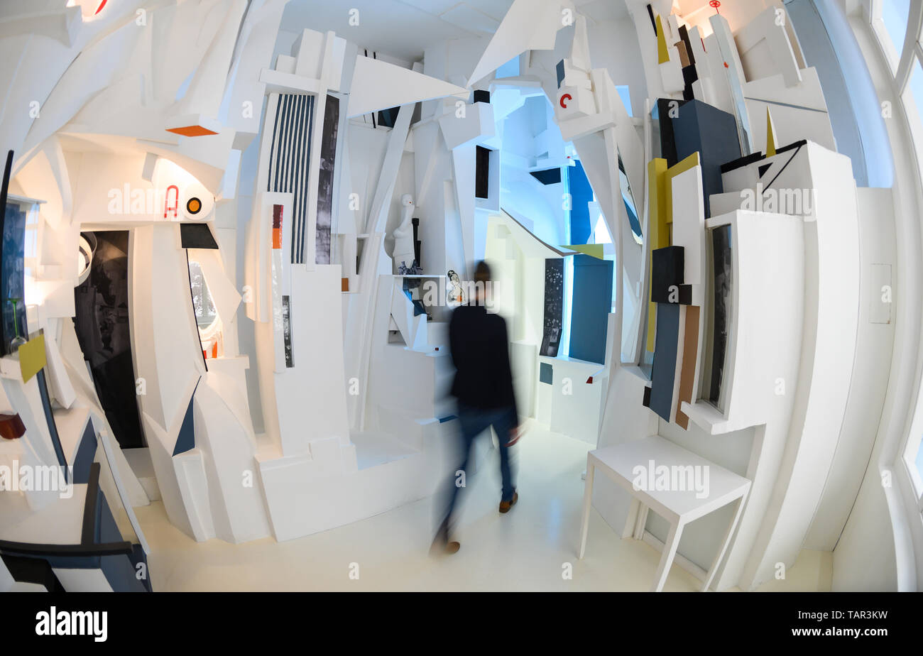 Hanover, Germany. 27th May, 2019. A woman walks in the Sprengel Museum through a reconstruction of the 'Merzbau' (1981-1983) by Kurt Schwitters. In 2019 the Sprengel Museum celebrates the 100th birthday of Merz with an exhibition of over 200 exhibits. Credit: Christophe Gateau/dpa/Alamy Live News Stock Photo