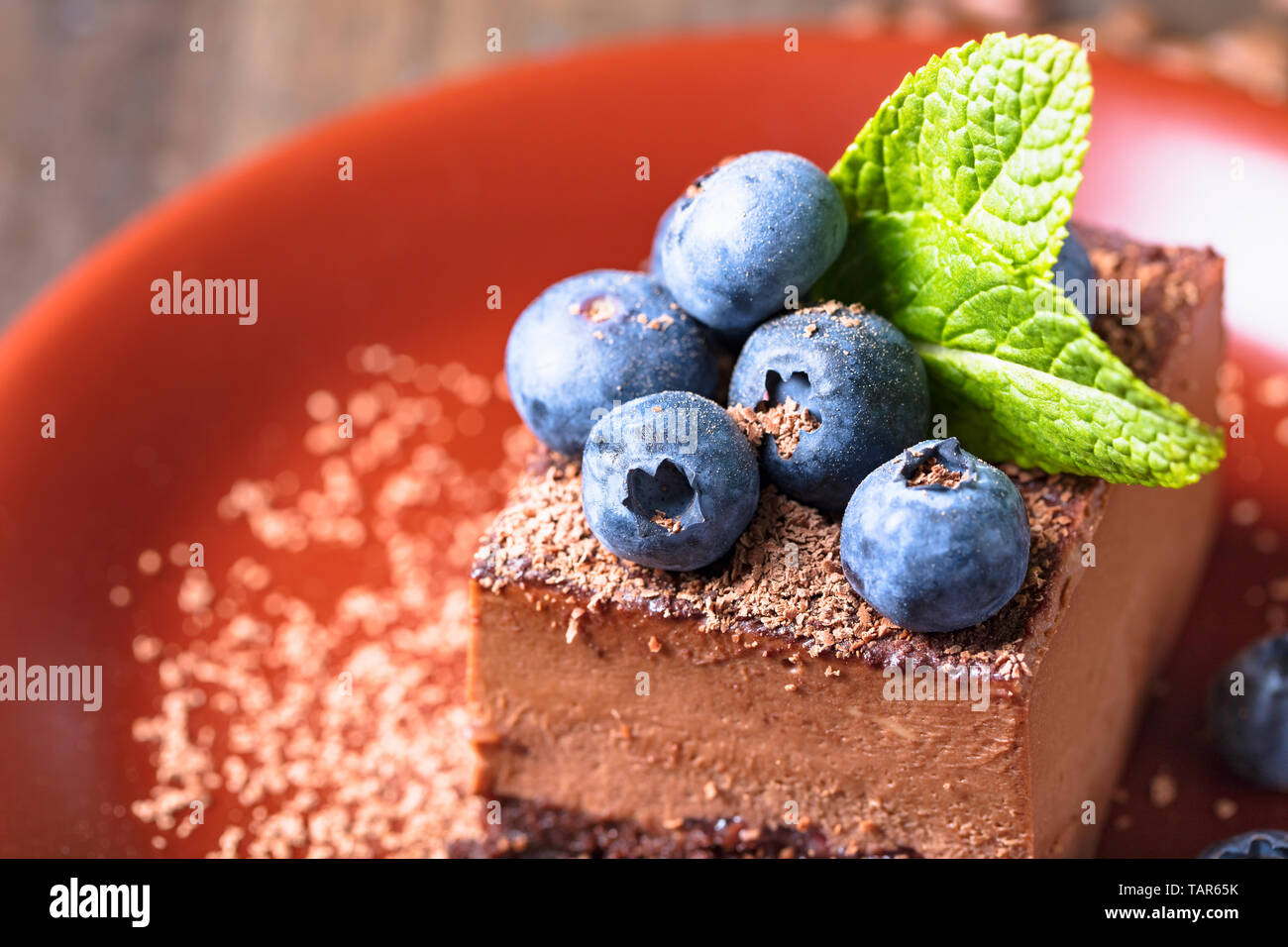 Close-up of chocolate cake with blueberries and mint on a brown plate ...