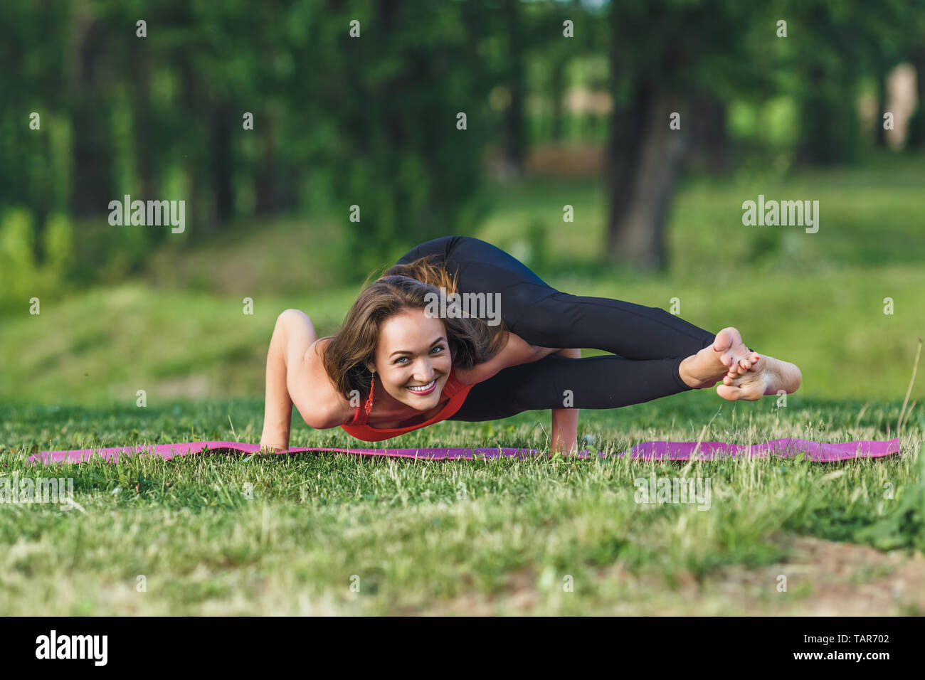 Young woman doing yoga exercises in the summer city park. Health lifestyle concept. Stock Photo