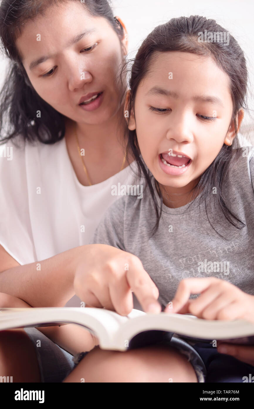 Close up mother and daughter read books together. Women teaching girl to reading a book. Child studying with mom. Stock Photo
