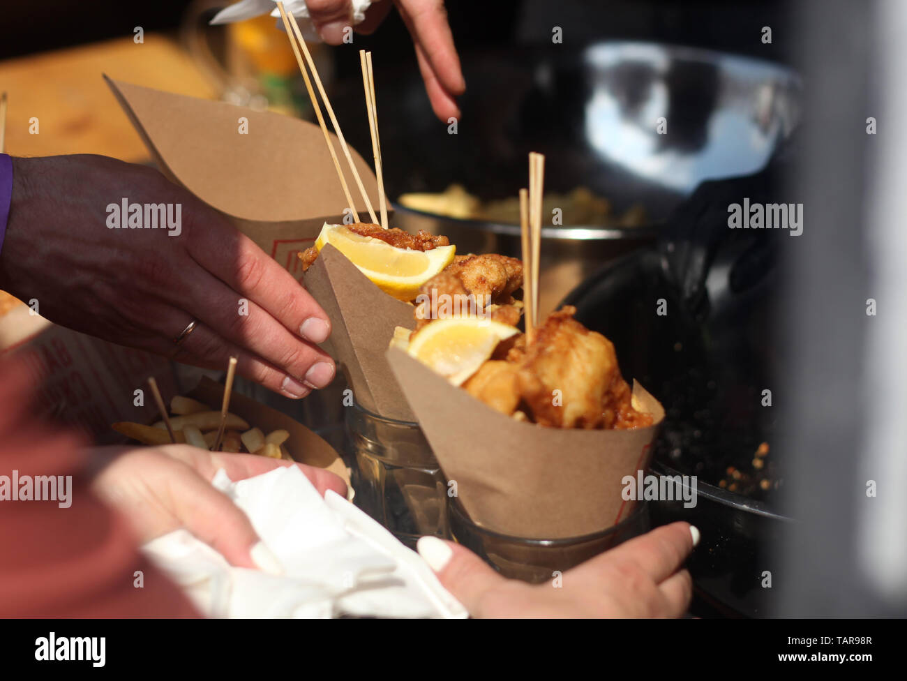 Street food festival. Picture of fish and chips with hands of event guests  Stock Photo - Alamy