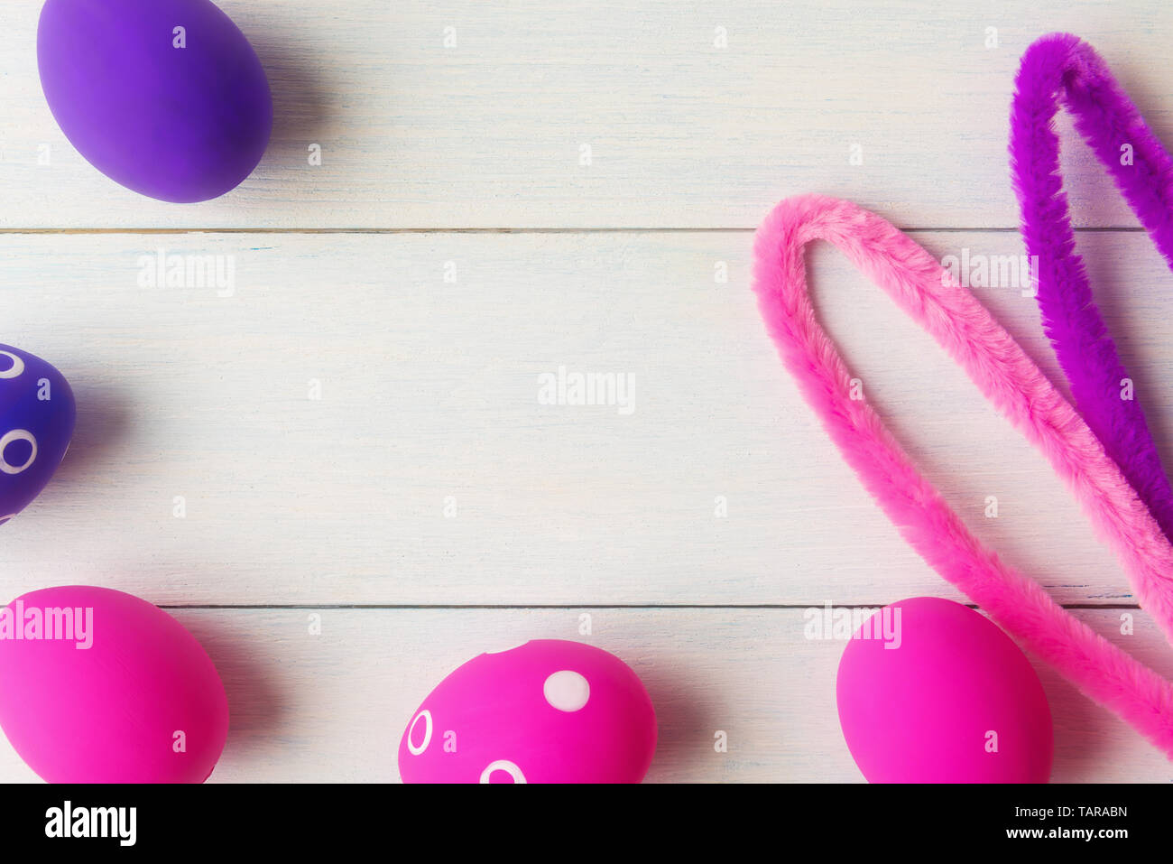 Bunny ears and decorative pink and purple eggs on wooden background Stock Photo