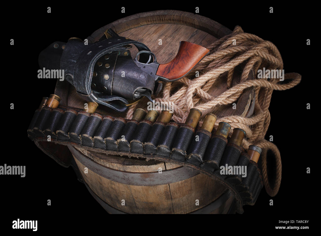 Old wild west gun with cartridges and gunbelt on wooden barrel Stock
