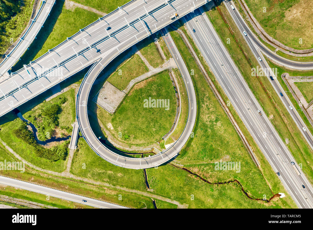 Big road junction fragment on green land aerial view, Highway intersection with traffic at sunny day Stock Photo