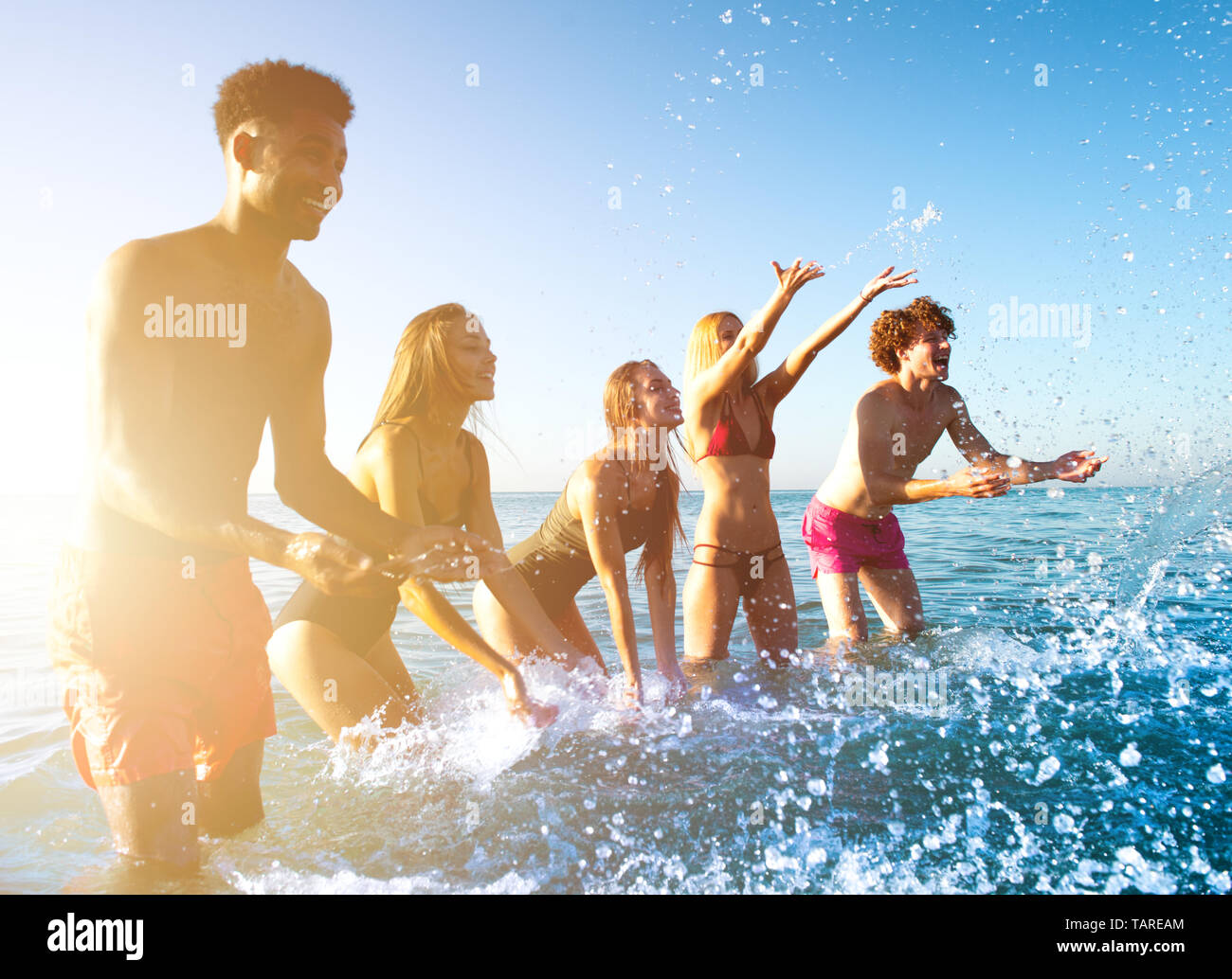 Group of friends having fun at the beach with water sea Stock Photo