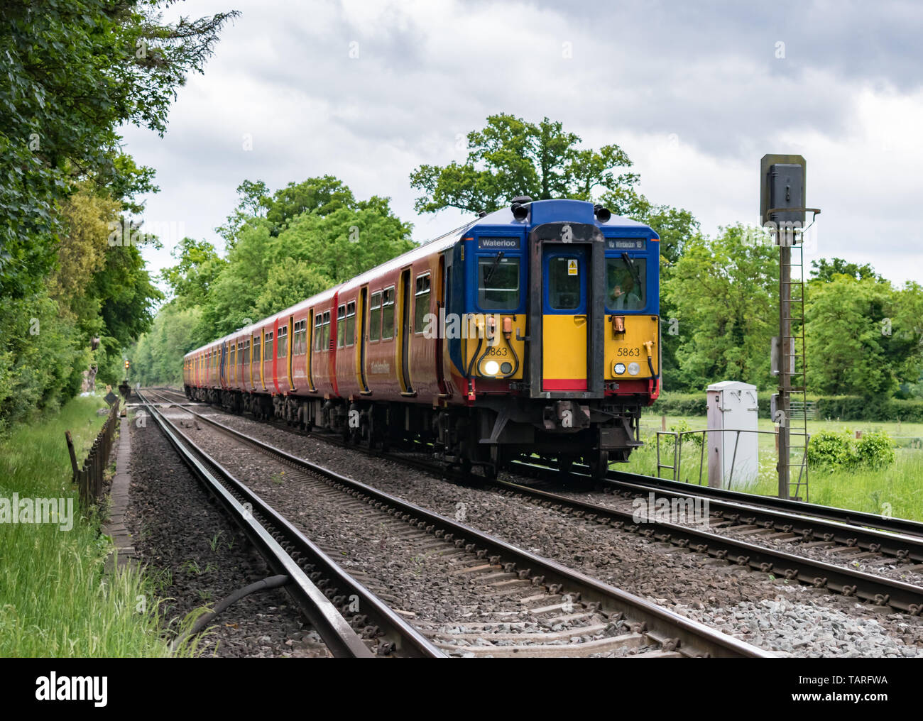 A train driver waves as his Class 455 South Western Railway passenger service train passes a signal in the Surrey countryside, heading for Waterloo. Stock Photo