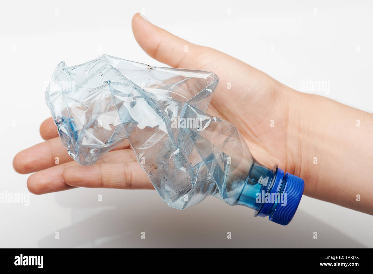 Recycling plastic theme. Crushed blue plastic bottle in hand palm Stock Photo
