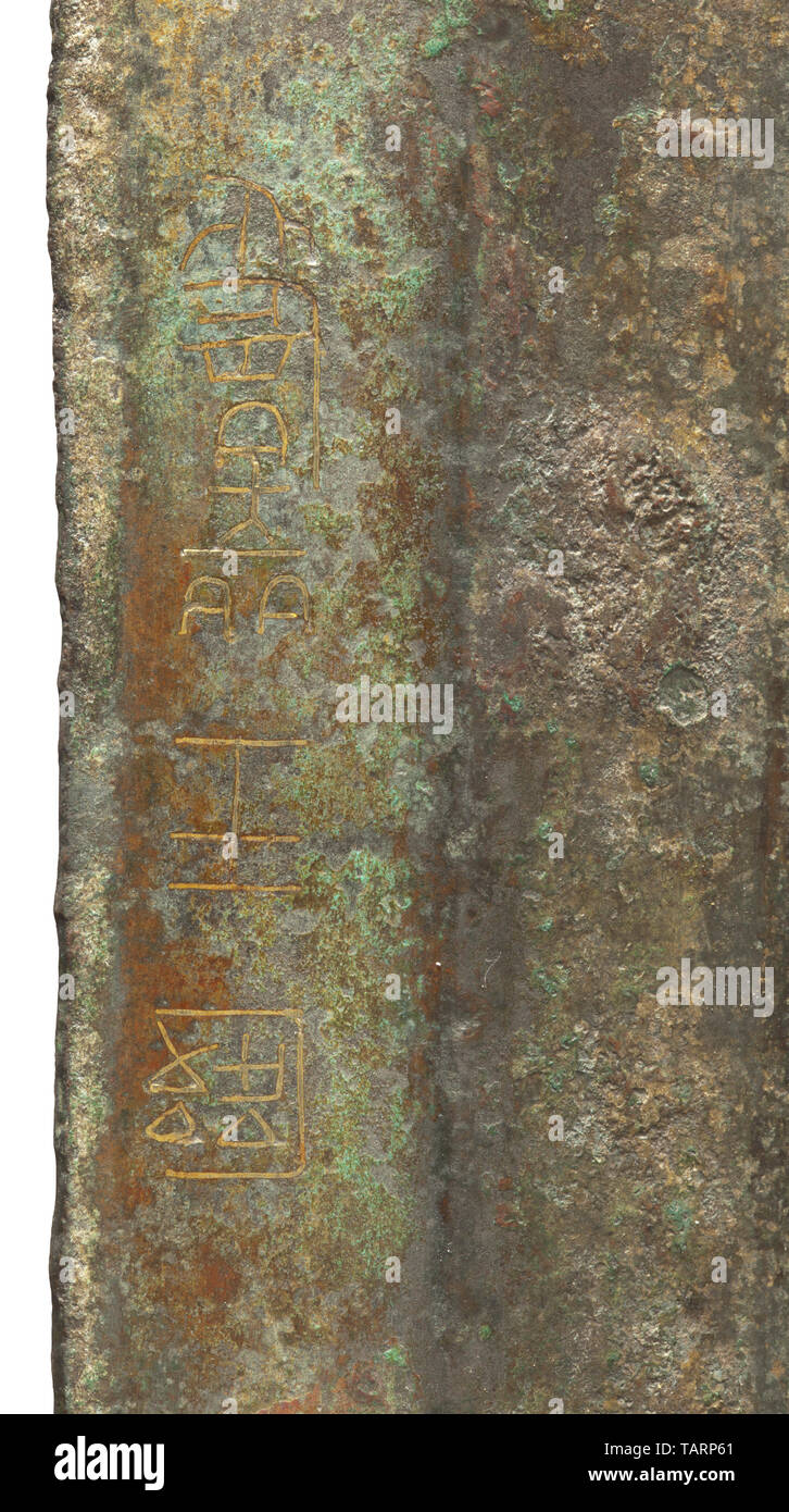 The bronze blade of a Chinese sword, bearing an inscription, Eastern Zhou, 5th - early 3rd century BC, Sturdy, solid blade with a broad tang, pronounced medial ridge and continuous, prominent, offset bevel, approximately 3 mm wide. The blade tapering almost imperceptibly towards the tip, the edges coming sharply together just before the point. On one side, to the left of the medial ridge, the upper part of the blade bears an inscription wrought in gold wire inlays. Dark green patina, overlaid with incrustation. Width of the tang 2.7 cm. Maximum w, Additional-Rights-Clearance-Info-Not-Available Stock Photo