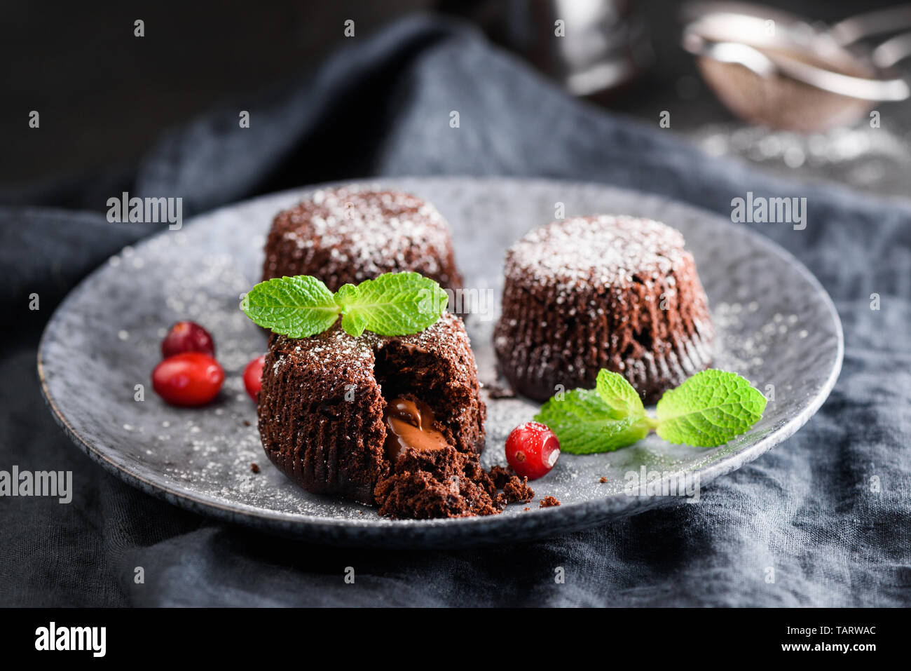 Lava chocolate cakes decorated with mint leaf and red berries on plate. Dark food photo. Tasty chocolate dessert Stock Photo