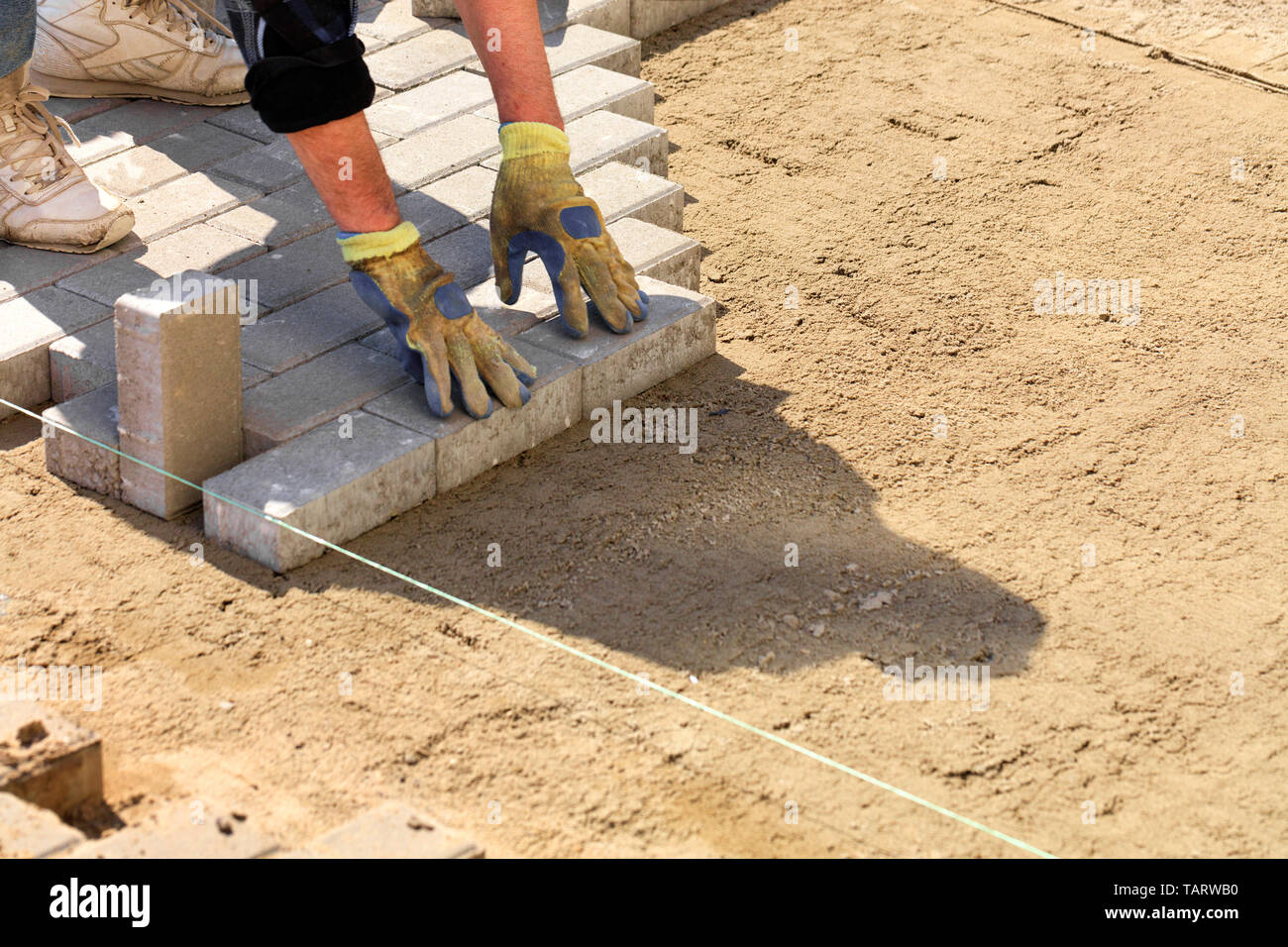 Paving Thread The worker puts the paving slabs along the stretched thread on the ...