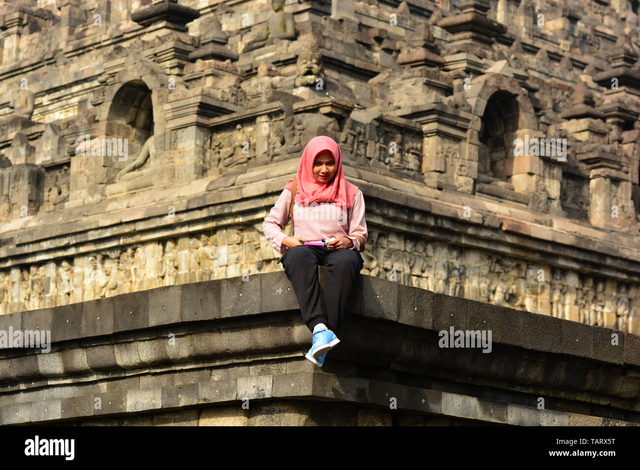BOROBUDUR/ JAVA- AUGUST 23, 2017. Young muslim woman using smart phone in Borobudur Temple, Indonesia Stock Photo