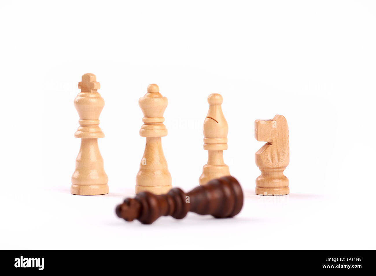 Row of white wooden chess pieces. Teamwork and cooperation, loser black king - Isolated on white background. Stock Photo