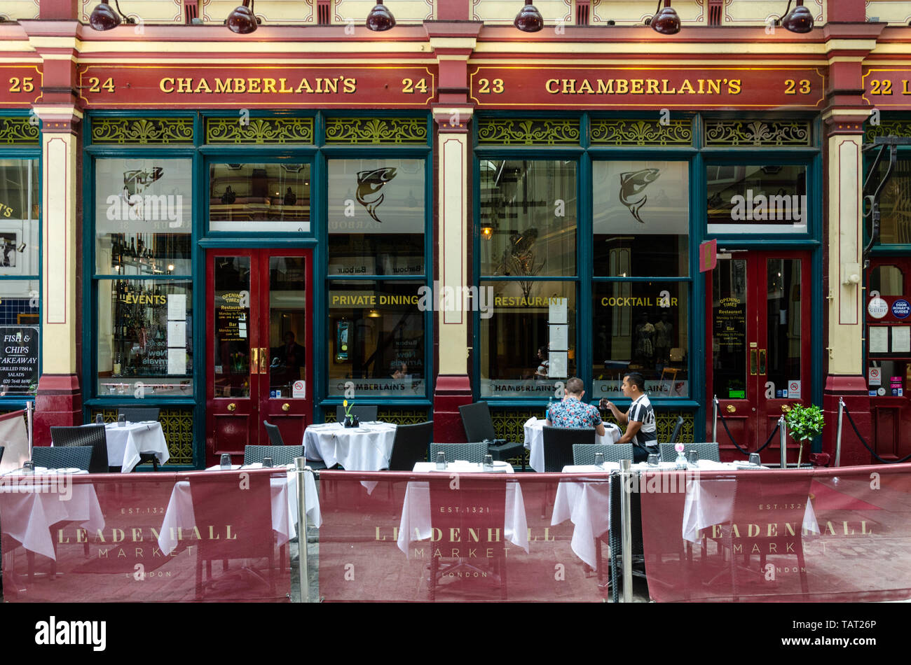 A couple sit and eat at a table outside Chamerlain's restaurant in Leandenhall Market in the financial disrict of The City of London, UK Stock Photo