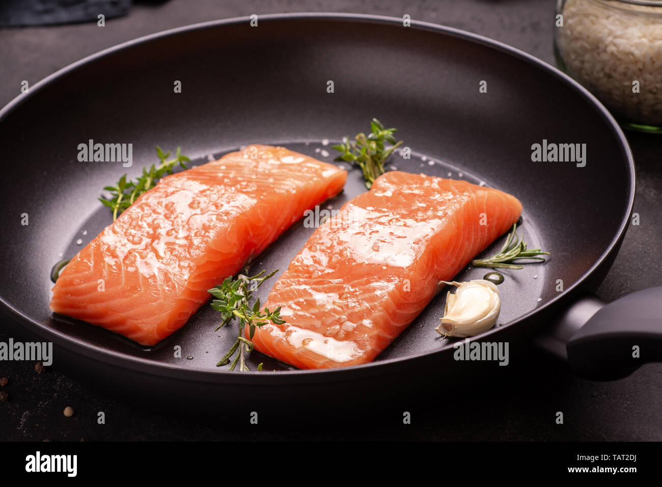 Fresh and Raw Salmon Steaks in Frying Pan with Thyme and Garlic Stock Photo