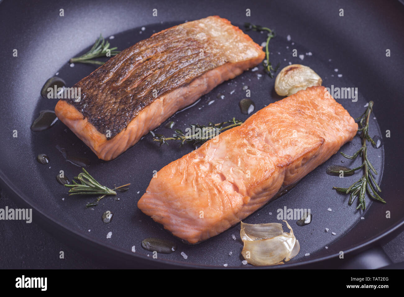Grilled Salmon Fillets in Black Frying Pan with Rosemary and Garlic Stock Photo