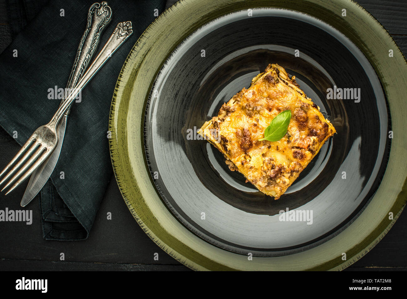 Italian Lasagne with Minced Beef and Green Basil on Dark Plate Stock Photo